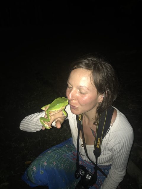 Clove holding a tree frog in the jungle at night